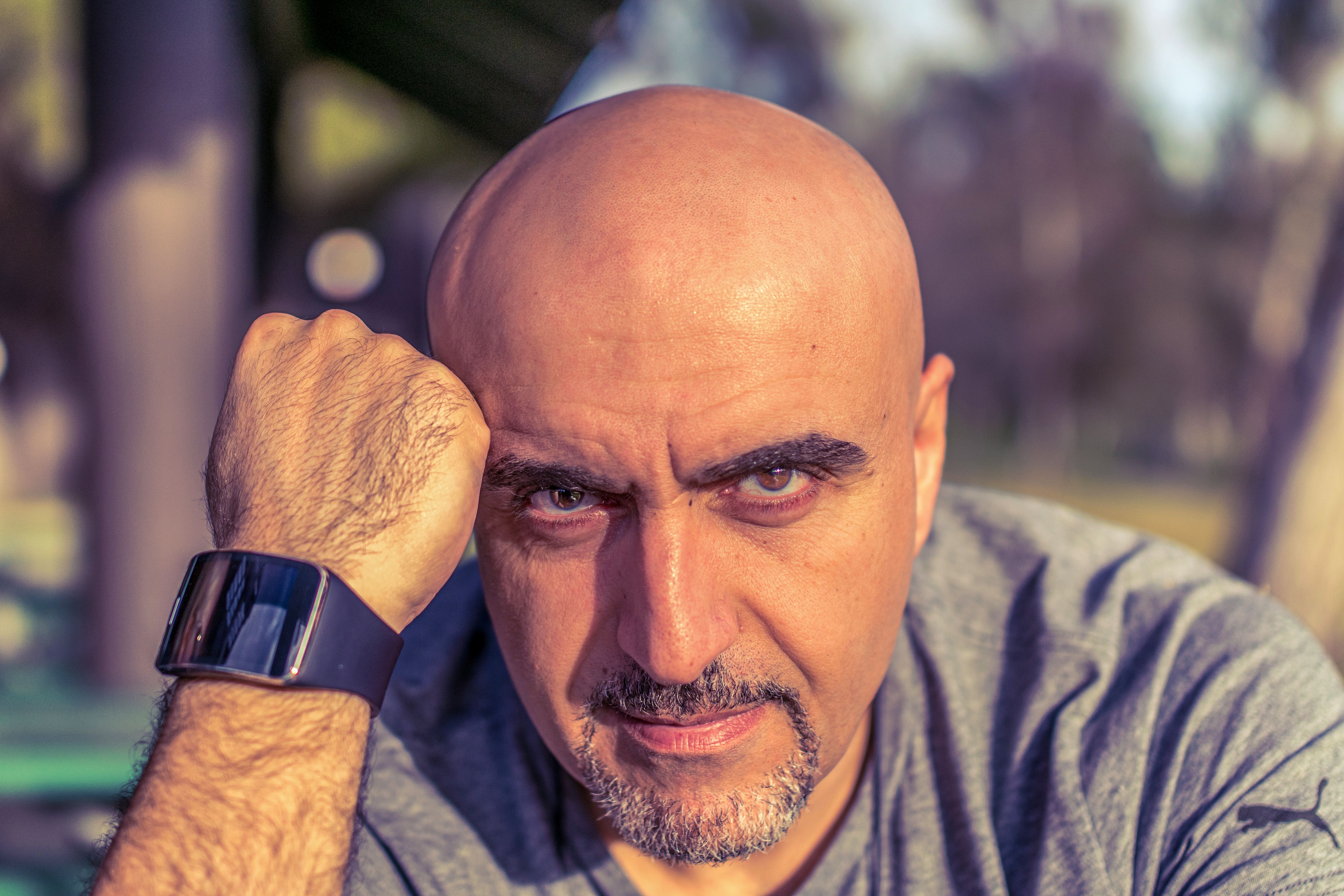 Bald man with smartwatch in an outdoor portrait setting, exuding confidence.
